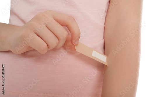 Preteen girl putting sticking plaster onto arm on white background  closeup