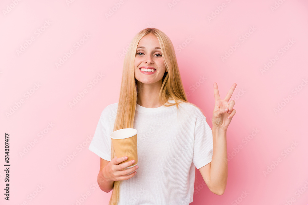 Young blonde girl holding a takeaway coffee showing number two with fingers. Young blonde girl holding a takeaway coffee showing number two with fingers.