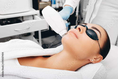 Photos Beautician removes facial hair of a brunette woman with a medical laser