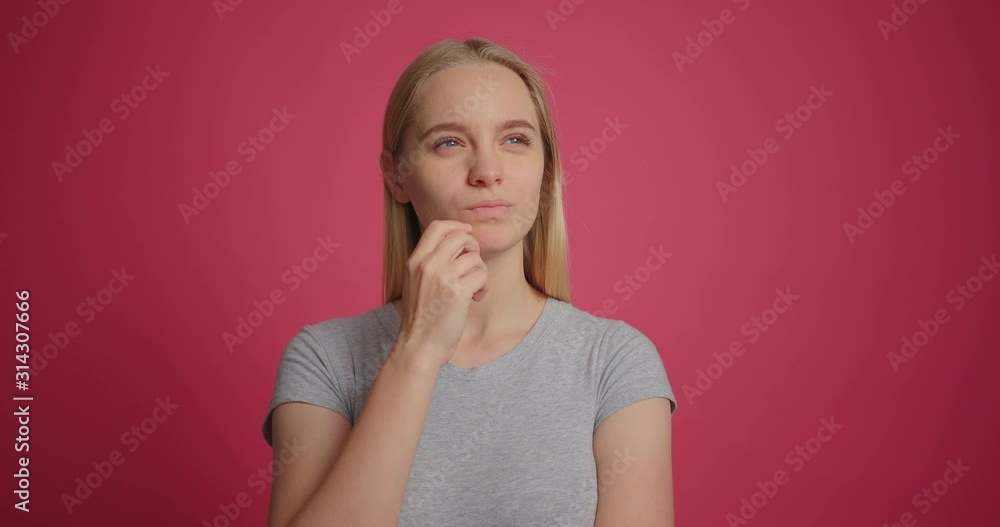 Pensive blonde girl thinking and having an idea over pink wall background Pensive blonde girl thinking and having an idea over pink wall background