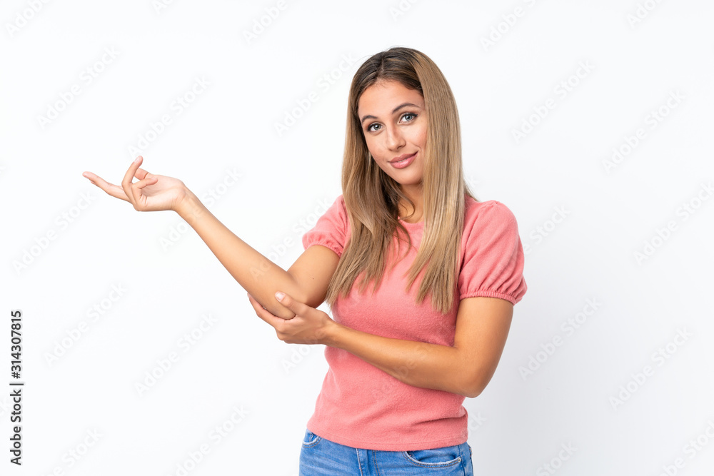 Young blonde woman over isolated white background extending hands to the side for inviting to come Young blonde woman over isolated white background extending hands to the side for inviting to come
