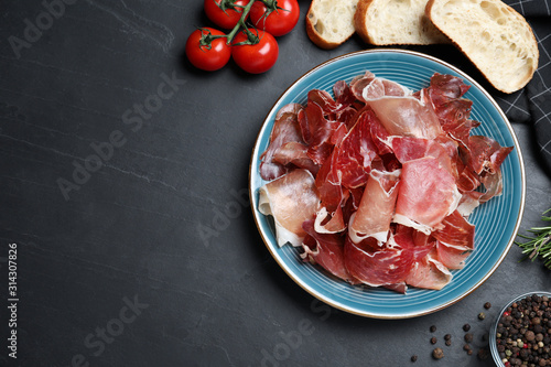 Tasty prosciutto served on black table, flat lay. Space for text
