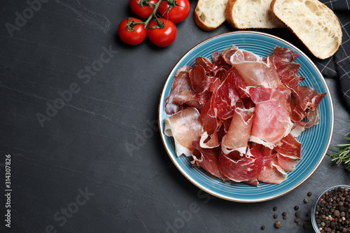 Tasty prosciutto served on black table, flat lay. Space for text photo