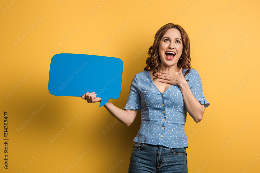 Naklejka premium excited girl laughing while holding speech bubble on yellow background