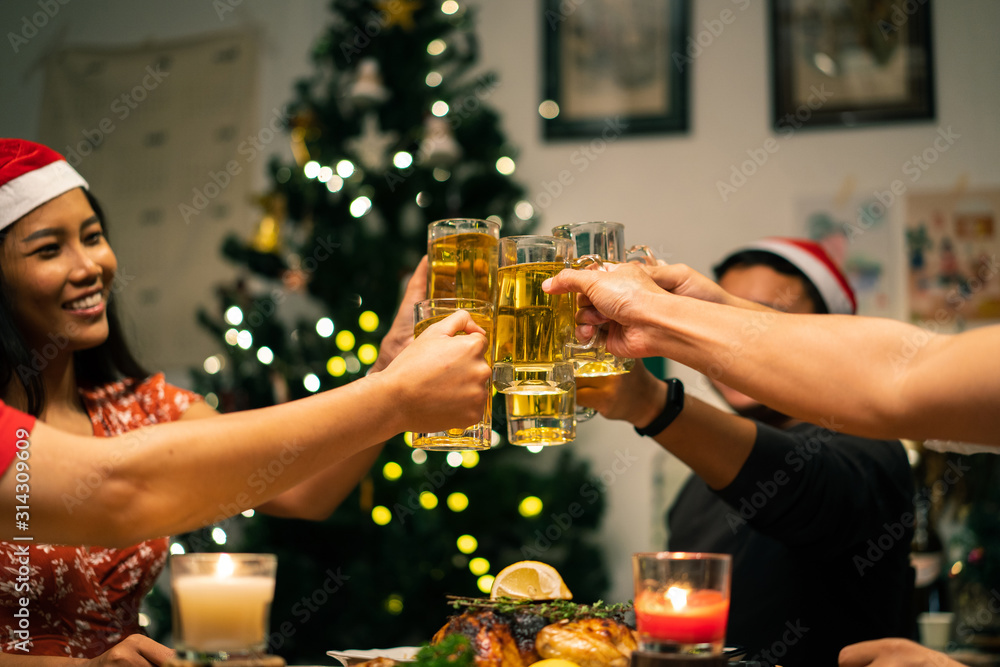 Group of Asian people have a dinner party and beer at home. They clink a glass of beer.