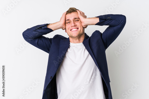 Young business caucasian man laughs joyfully keeping hands on head. Happiness concept.