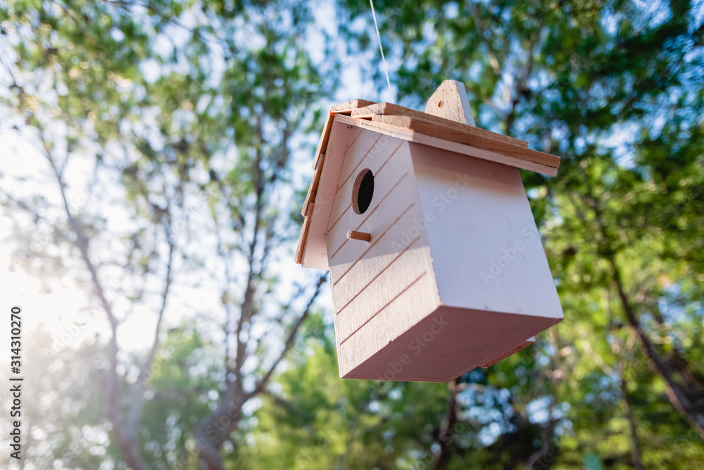 Wooden house for little birds hanging on a tree in a garden.