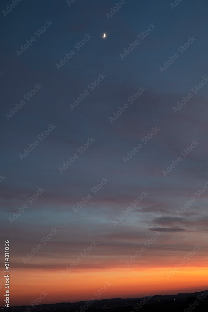 Ciel de lever de soleil, lueur orange sur ciel bleu nuit.