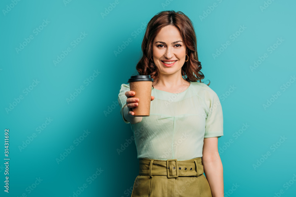 attractive, smiling woman showing paper cup on blue background attractive, smiling woman showing paper cup on blue background