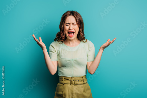 angry woman screaming with closed eyes on blue background