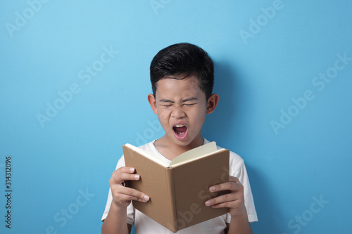 Asian student boy tired sleepy and yawning when reading a book