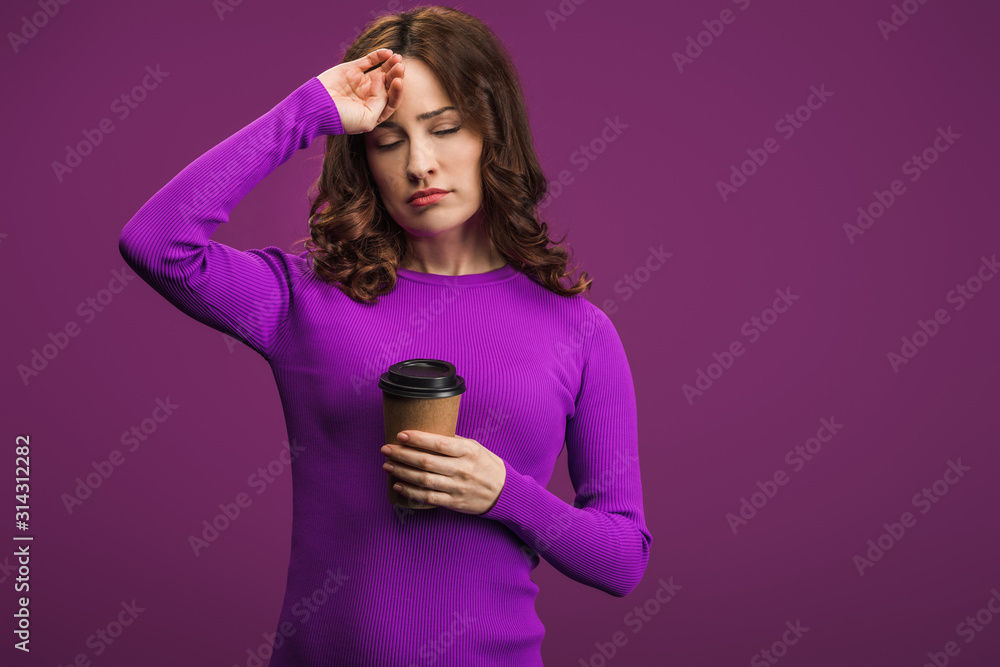 exhausted girl touching forehead while holding coffee to go on purple background exhausted girl touching forehead while holding coffee to go on purple background