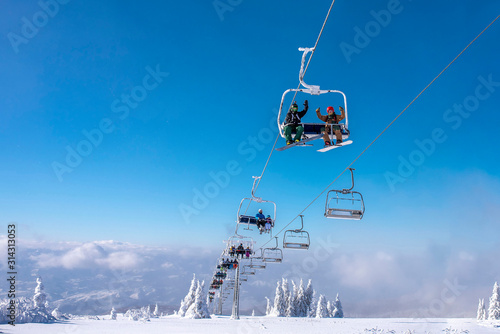 People enjoying winter sports. Skiers on chairlift at mountain ski resort  photo