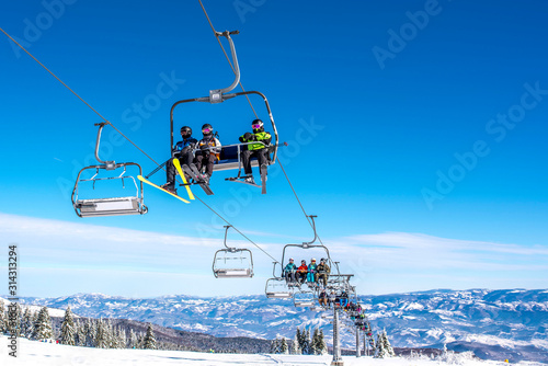 Skiers on chairlift at mountain ski resort with beautiful winter landscape in the background photo