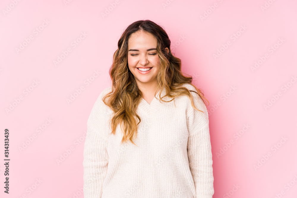 Young curvy woman posing in a pink background isolated laughs and closes eyes, feels relaxed and happy. Young curvy woman posing in a pink background isolated laughs and closes eyes, feels relaxed and happy.