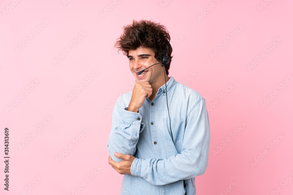 Young caucasian man over isolated pink background working with headset looking side Young caucasian man over isolated pink background working with headset looking side