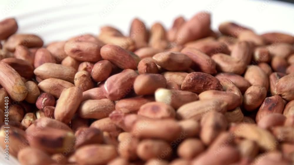 Male hand grabs roasted peanuts and pours them back into plate Male hand grabs roasted peanuts and pours them back into plate