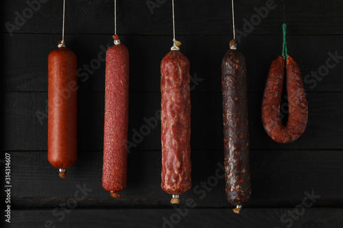 Delicious different hanging sausages on wooden background