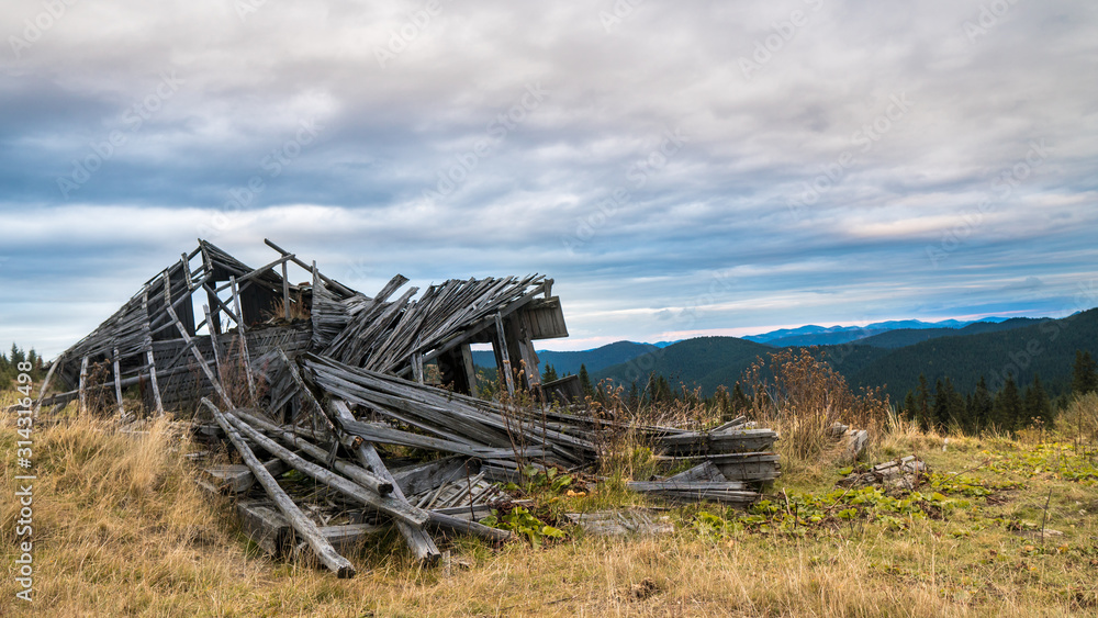 A pile of gray wooden planks of old ruined tourist shelter in the mountains.