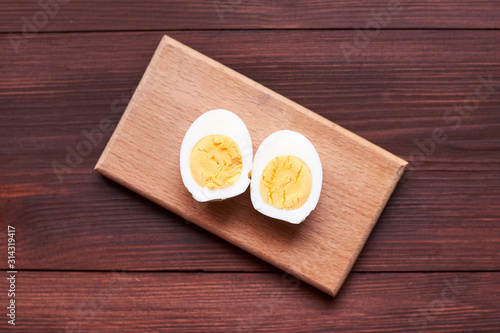 Boiled chicken egg cut into two halves on a wooden background.