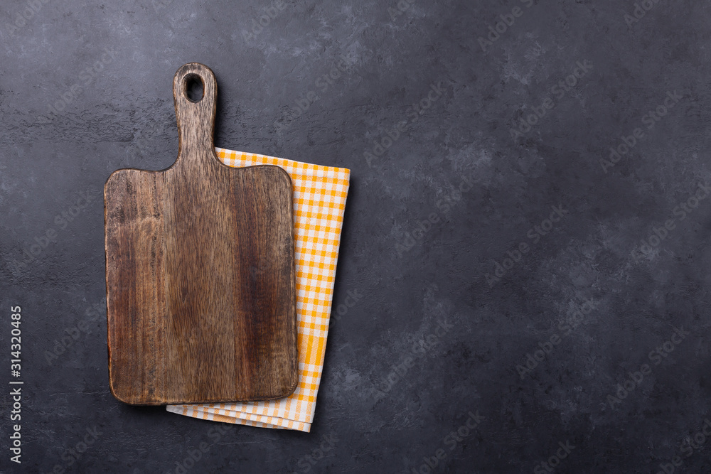 Fototapeta premium Cutting board and linen napkin on dark stone table. Copy space