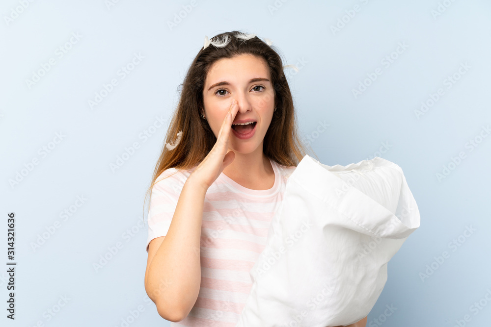 Young woman in pajamas over isolated blue background shouting with mouth wide open Young woman in pajamas over isolated blue background shouting with mouth wide open