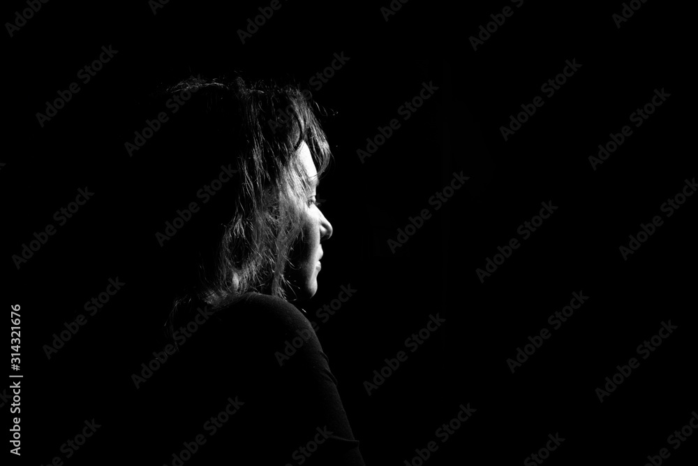silhouette in profile a lonely and sad girl on a black background. Black and white photo