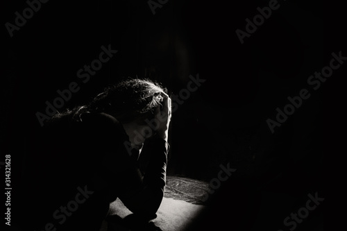 lonely and sad girl holding her head on a black background