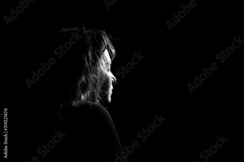 silhouette in profile a lonely and sad girl on a black background. Black and white photo