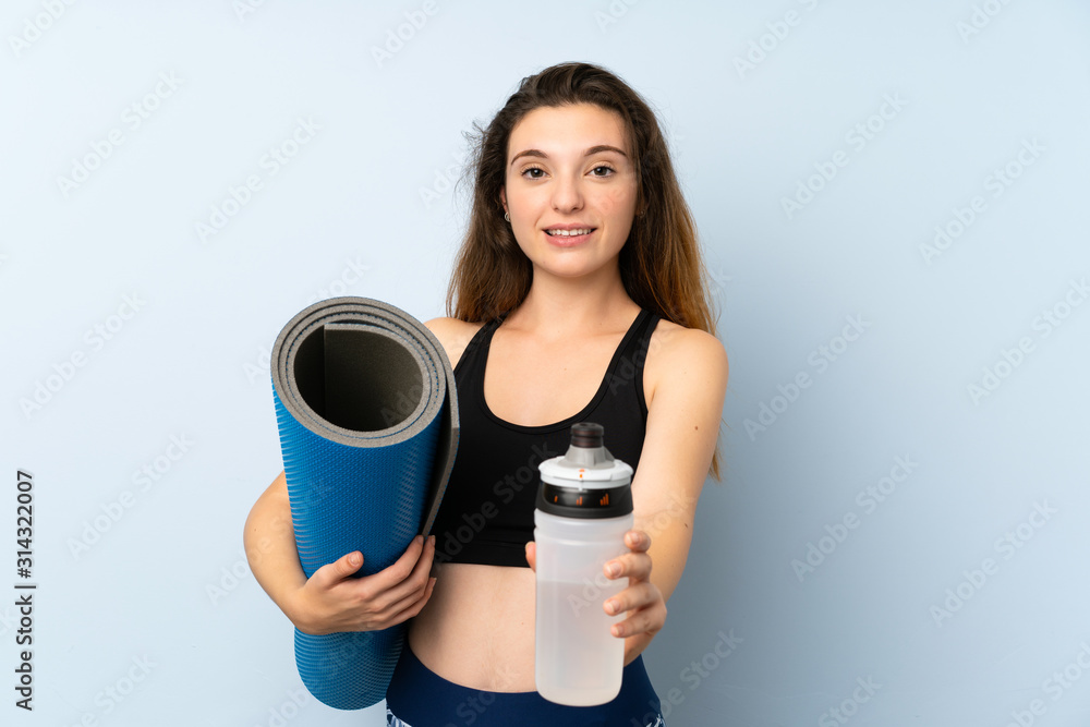 Young brunette girl with mat and a bottle of water over isolated background Young brunette girl with mat and a bottle of water over isolated background