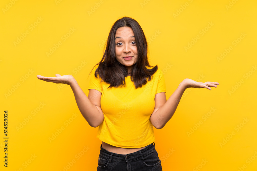 Young brunette girl over isolated background having doubts while raising hands Young brunette girl over isolated background having doubts while raising hands