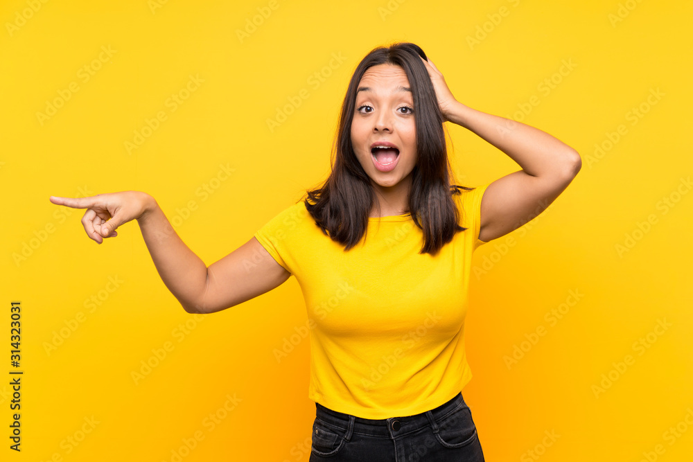 Young brunette girl over isolated background surprised and pointing finger to the side Young brunette girl over isolated background surprised and pointing finger to the side