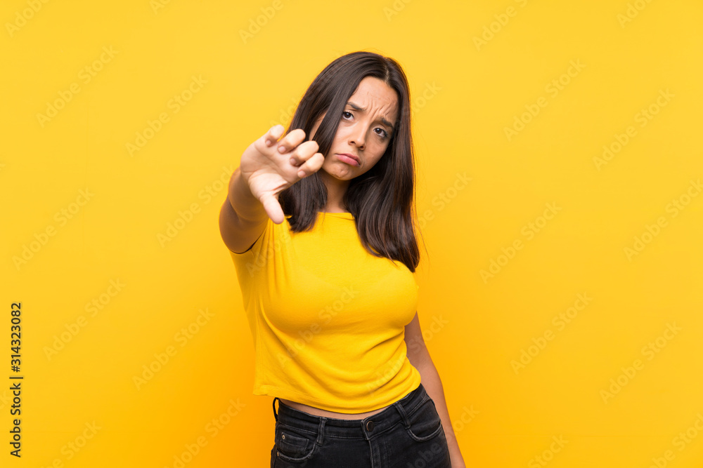 Young brunette girl over isolated background showing thumb down with negative expression Young brunette girl over isolated background showing thumb down with negative expression