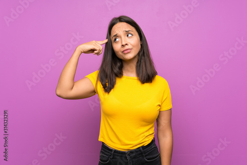 Young brunette girl over isolated background making the gesture of madness putting finger on the head