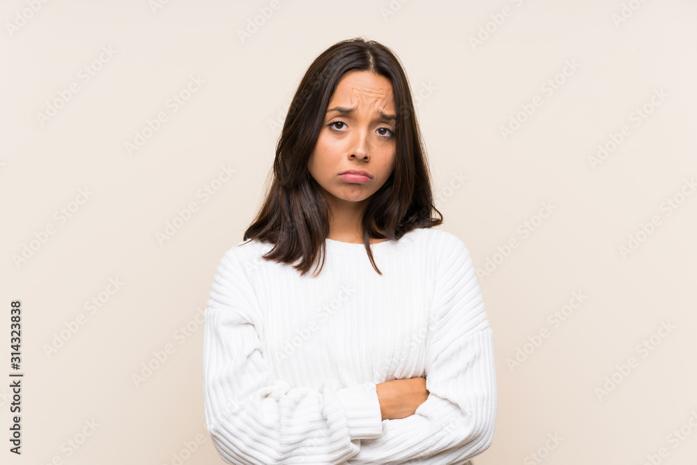Young brunette woman with white sweater over isolated background sad