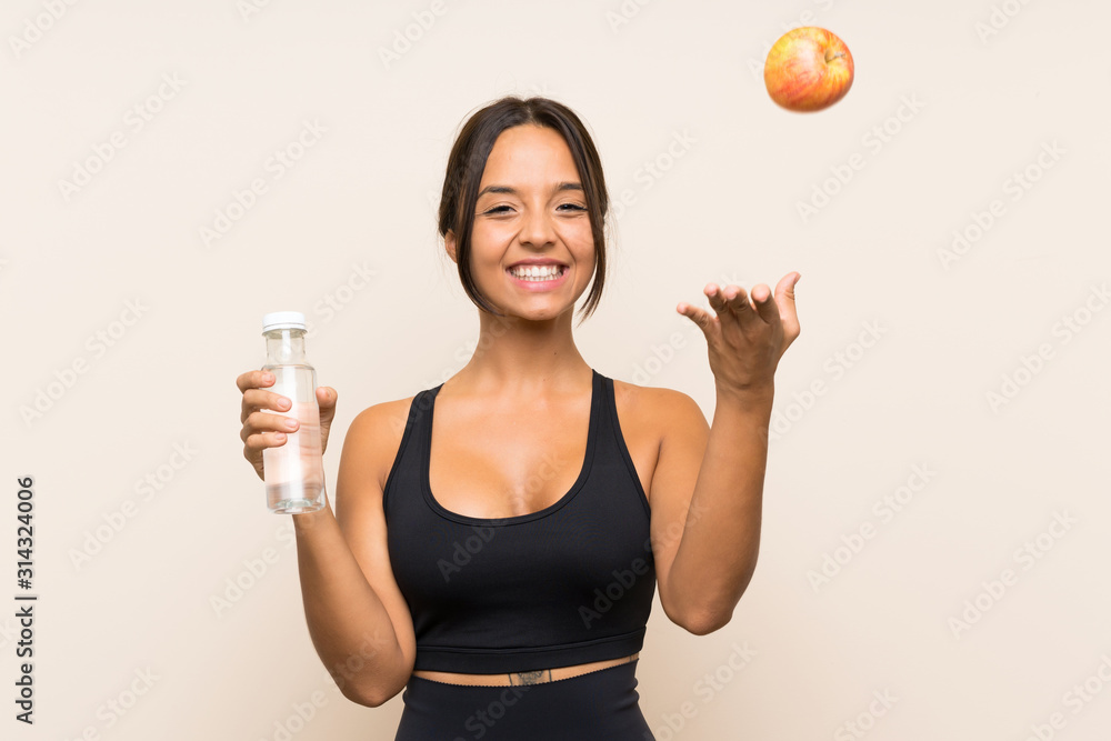 Young brunette girl with an apple and with a bottle of water over isolated background Young brunette girl with an apple and with a bottle of water over isolated background