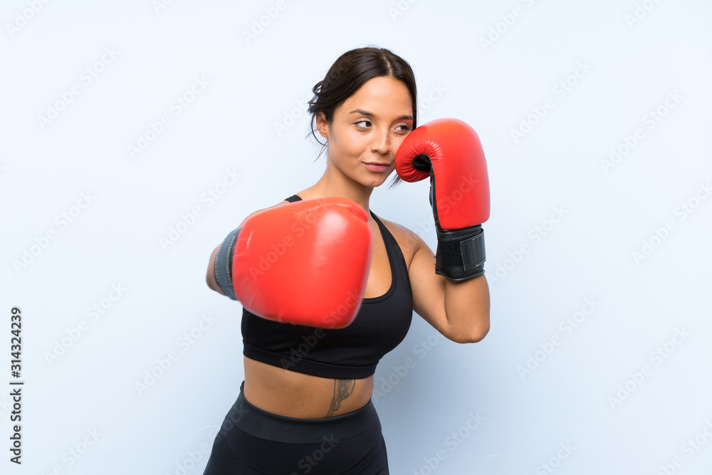 Young sport girl with boxing gloves over isolated blue background Young sport girl with boxing gloves over isolated blue background