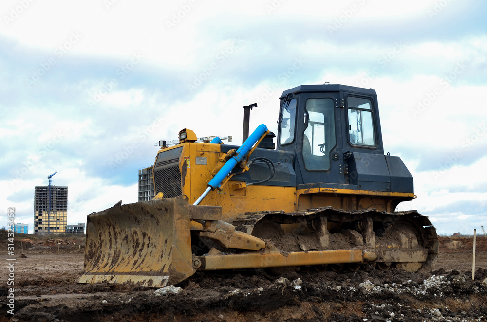 Track-type bulldozer during of large construction jobs at building site. Land clearing, grading, pool excavation, utility trenching, utility trenching and foundation digging. Earth-moving equipment.