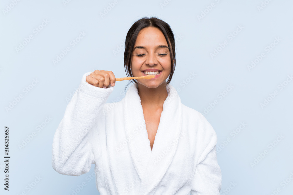 Young brunette girl in bathrobe with makeup over isolated blue background Young brunette girl in bathrobe with makeup over isolated blue background