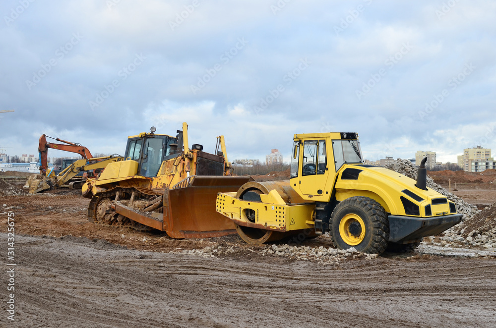 Soil Compactor and bulldozer at construction site. Vibration single-cylinder road roller leveling the ground for the construct of the foundation building