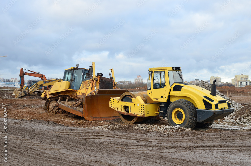 Soil Compactor and bulldozer at construction site. Vibration single-cylinder road roller leveling the ground for the construct of the foundation building Soil Compactor and bulldozer at construction site. Vibration single-cylinder road roller leveling the ground for the construct of the foundation building
