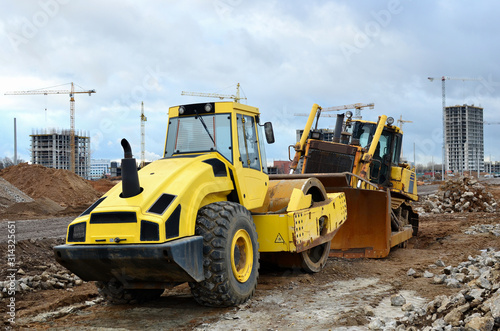 Soil Compactor and bulldozer at construction site. Vibration single-cylinder road roller leveling the ground for the construct of the foundation building