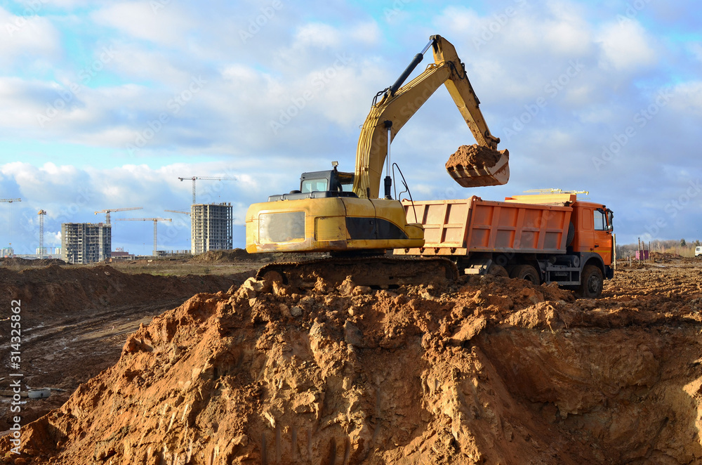 Excavator load the sand to the heavy dump truck on construction site. Excavators and dozers digs the ground for the foundation and construction of a new building. Apartment renovation program