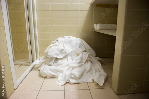 Pile of dirty used towels on the hotel bathroom floor. Housekeeping replace only the used towels on floor with clean ones. Saving water soap energy as a green policy. Stock Photo