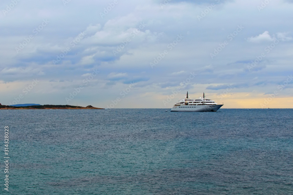 The large modern white private yacht moored in the Saronic Gulf. Travel and tourism concept. Cloudy sky in the background. Landscape panoramic view. Athens, Greece