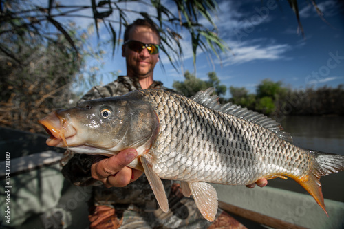 Angler holds big Carp fish and smiles
