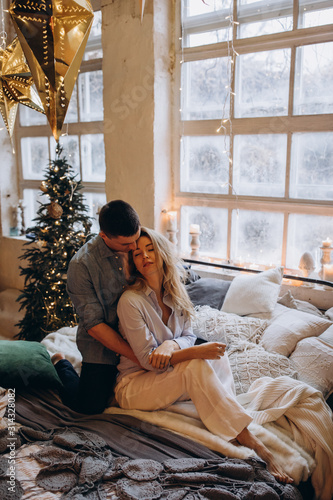 A guy with a girl is celebrating Christmas. A loving couple enjoys each other on New Year's Eve in a cozy home environment. New Year's love story.