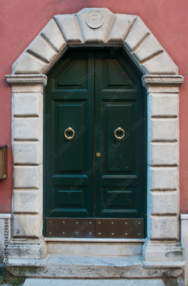 Green wood door with marble portal in Carrara, Tuscany