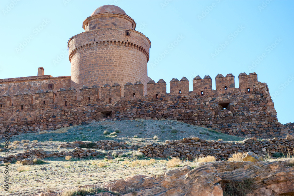 tower of the medieval spanish castle La Calahorra behind the outer wall in the light of the evening sun, Granada, Spain