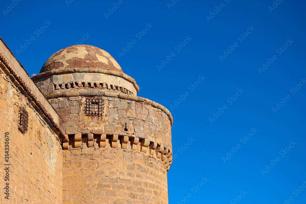 Tower and wall of medieval castle La Calahorra on the azure sky background